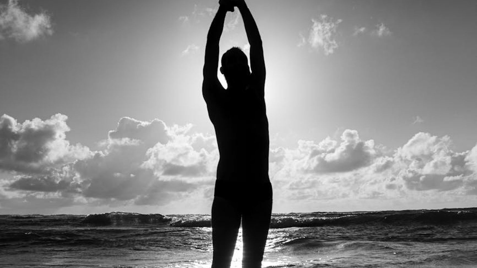 Person silhouette during sunrise doing a gentle stretching exercise.